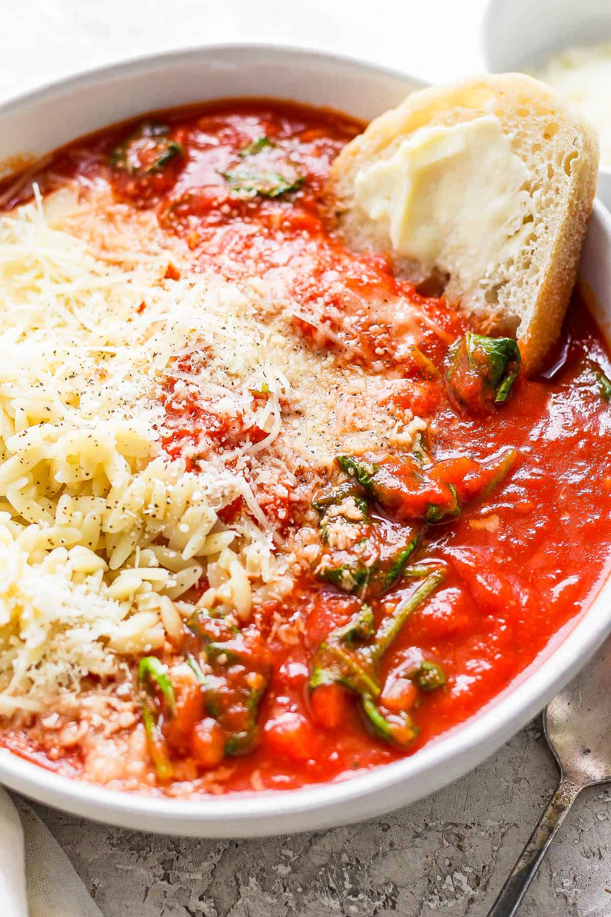 A bowl of tomato florentine soup over some cooked orzo.