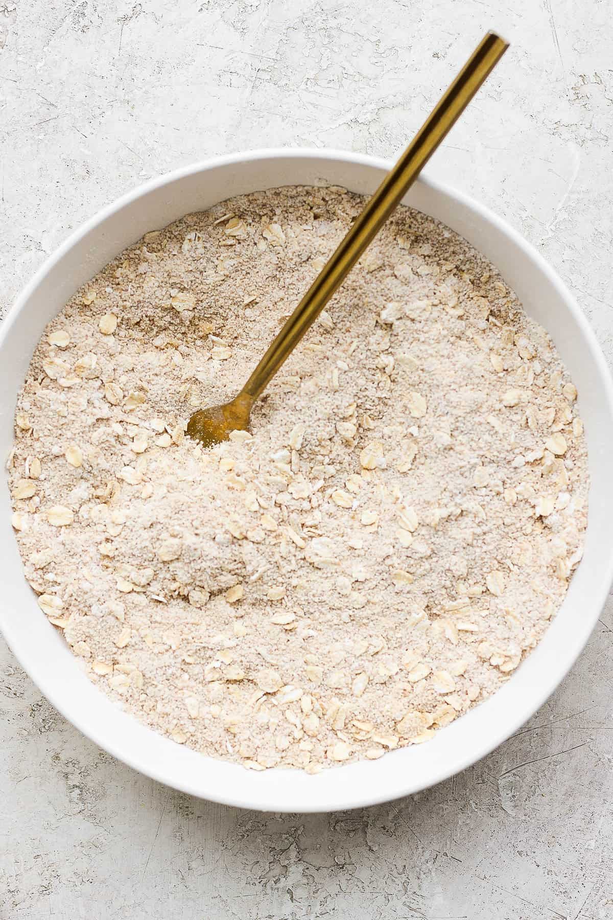 The dry ingredients all mixed together in a white bowl with a spoon.