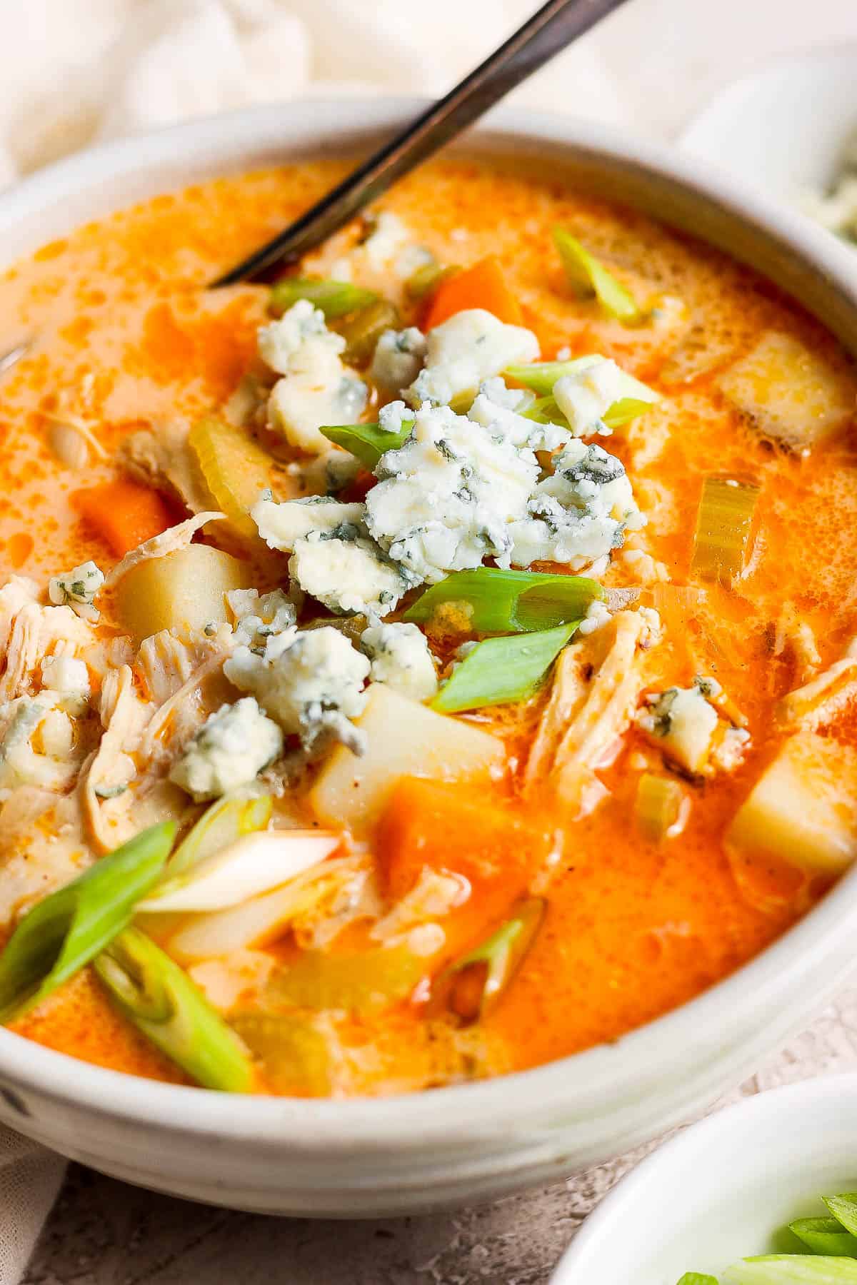 A bowl of buffalo chicken soup with a spoon in it.