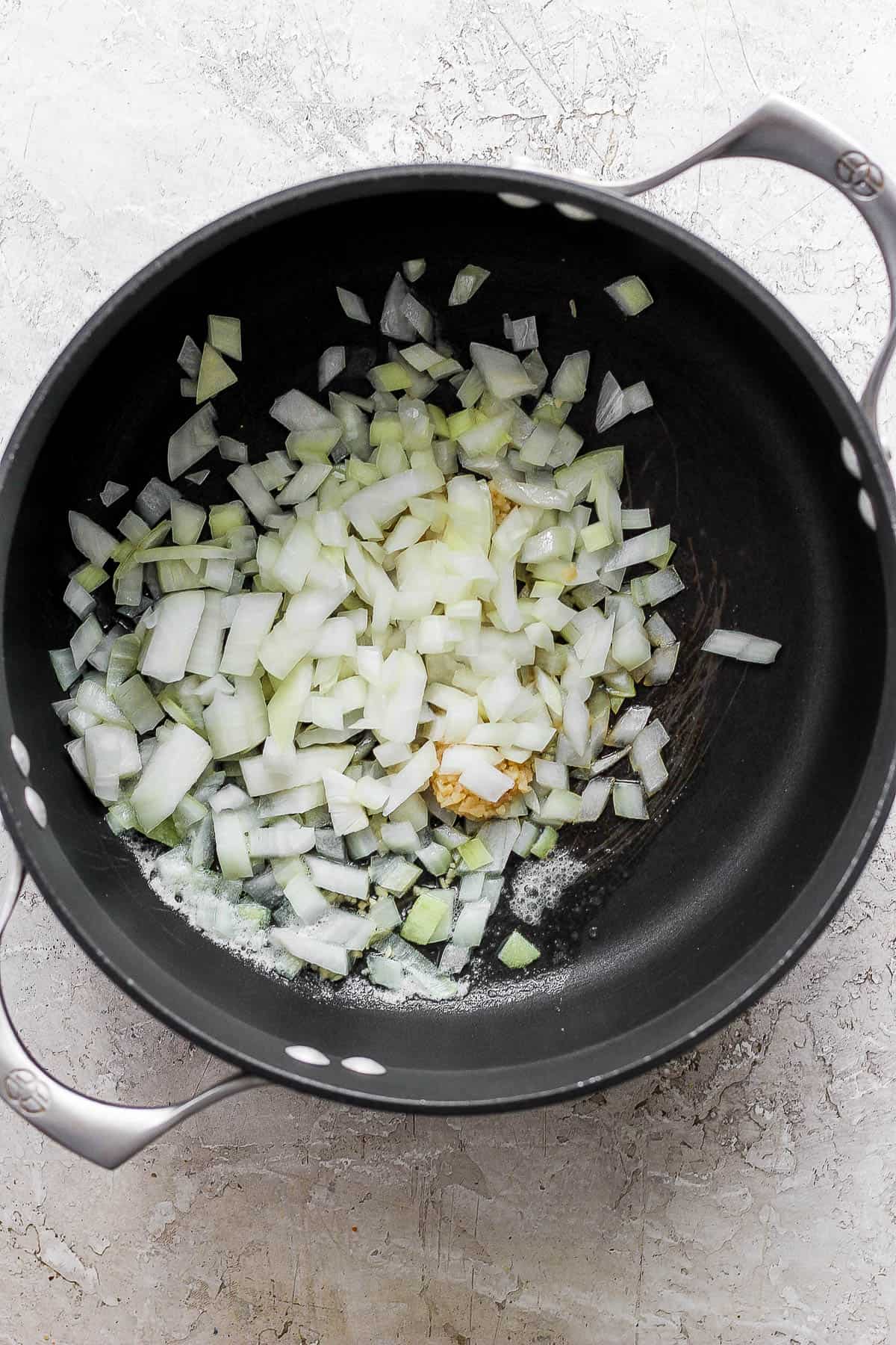 A large pot with melted butter and garlic and onion tossed in to sauté.