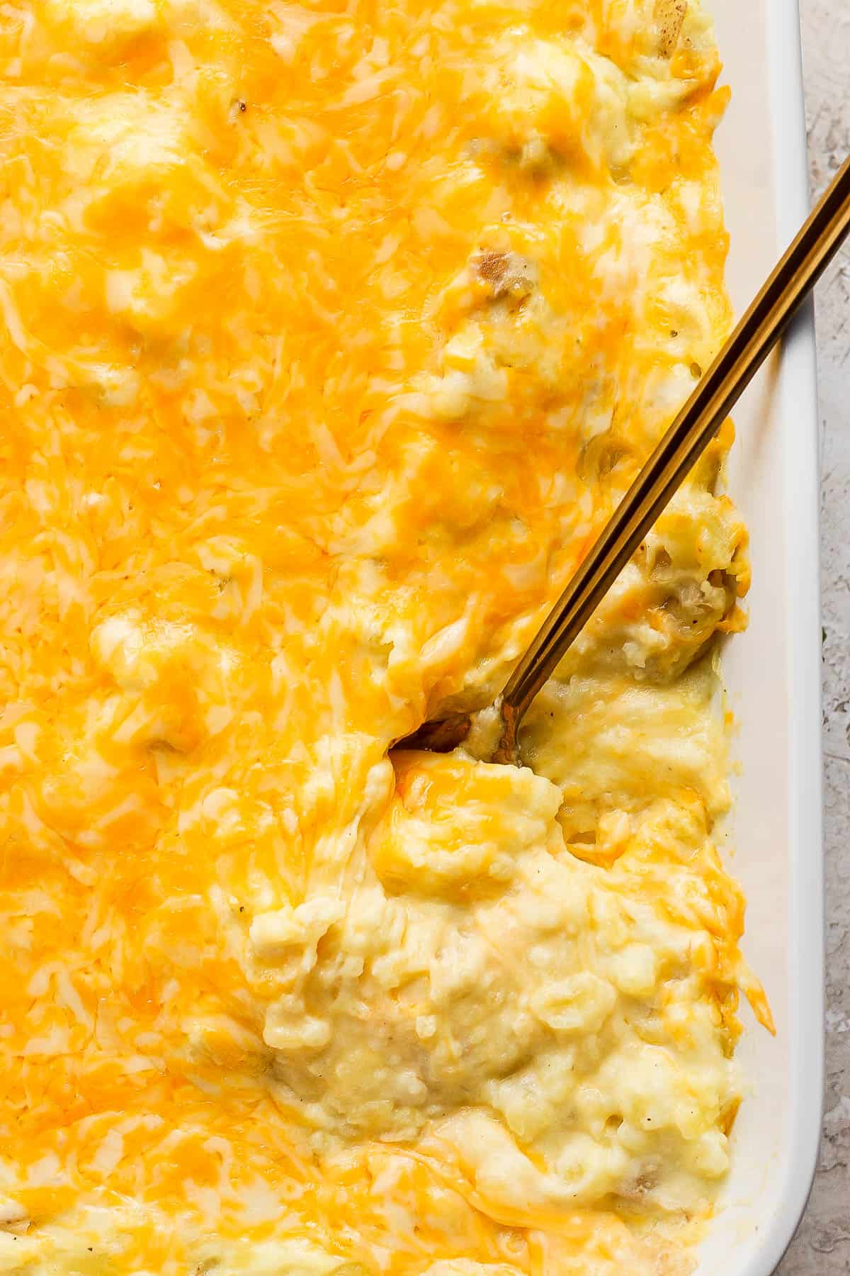 Fully baked cheese mashed potatoes with a spoon in it.
