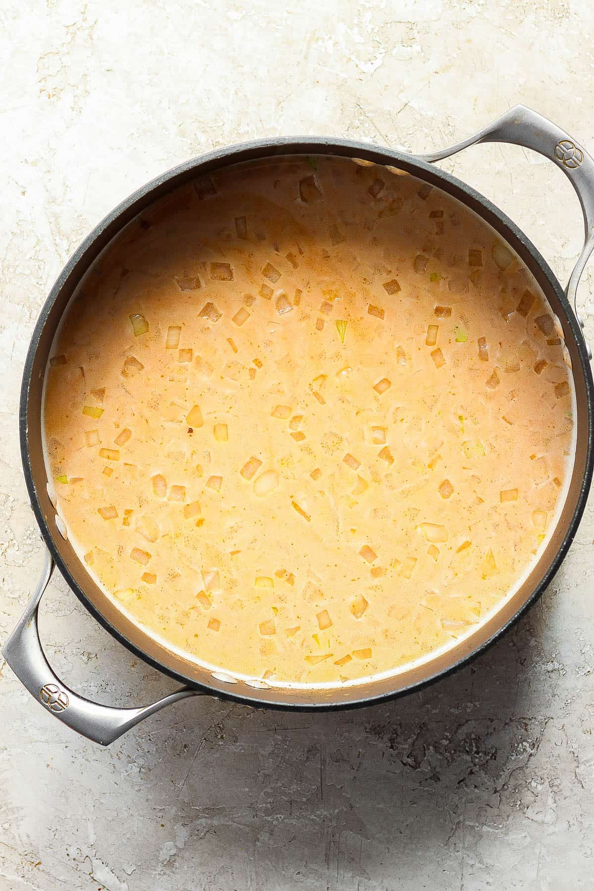 Chicken broth, coconut milk, lime juice, lime zest, garlic chili sauce, ginger, lemongrass, red curry paste, fish sauce, salt and pepper added to the pot.