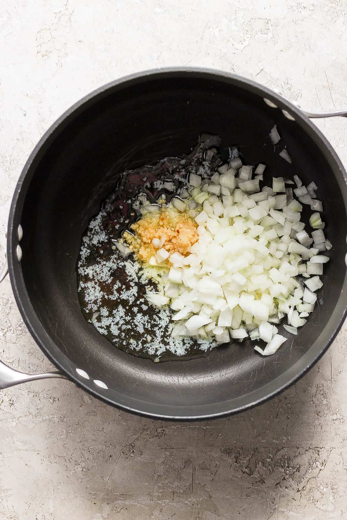 Garlic and onion sautéing in melted butter in a large pot.