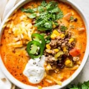 Top down shot of a bowl of creamy taco soup with jalapeno, cilantro, cheese and sour cream.