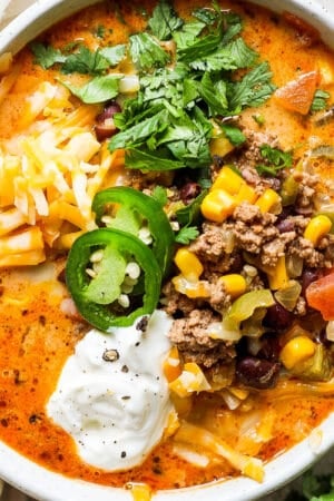 Top down shot of a bowl of creamy taco soup with jalapeno, cilantro, cheese and sour cream.