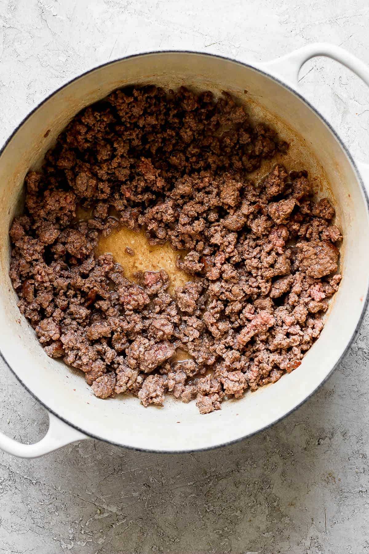 Ground beef browning in a large white pot.