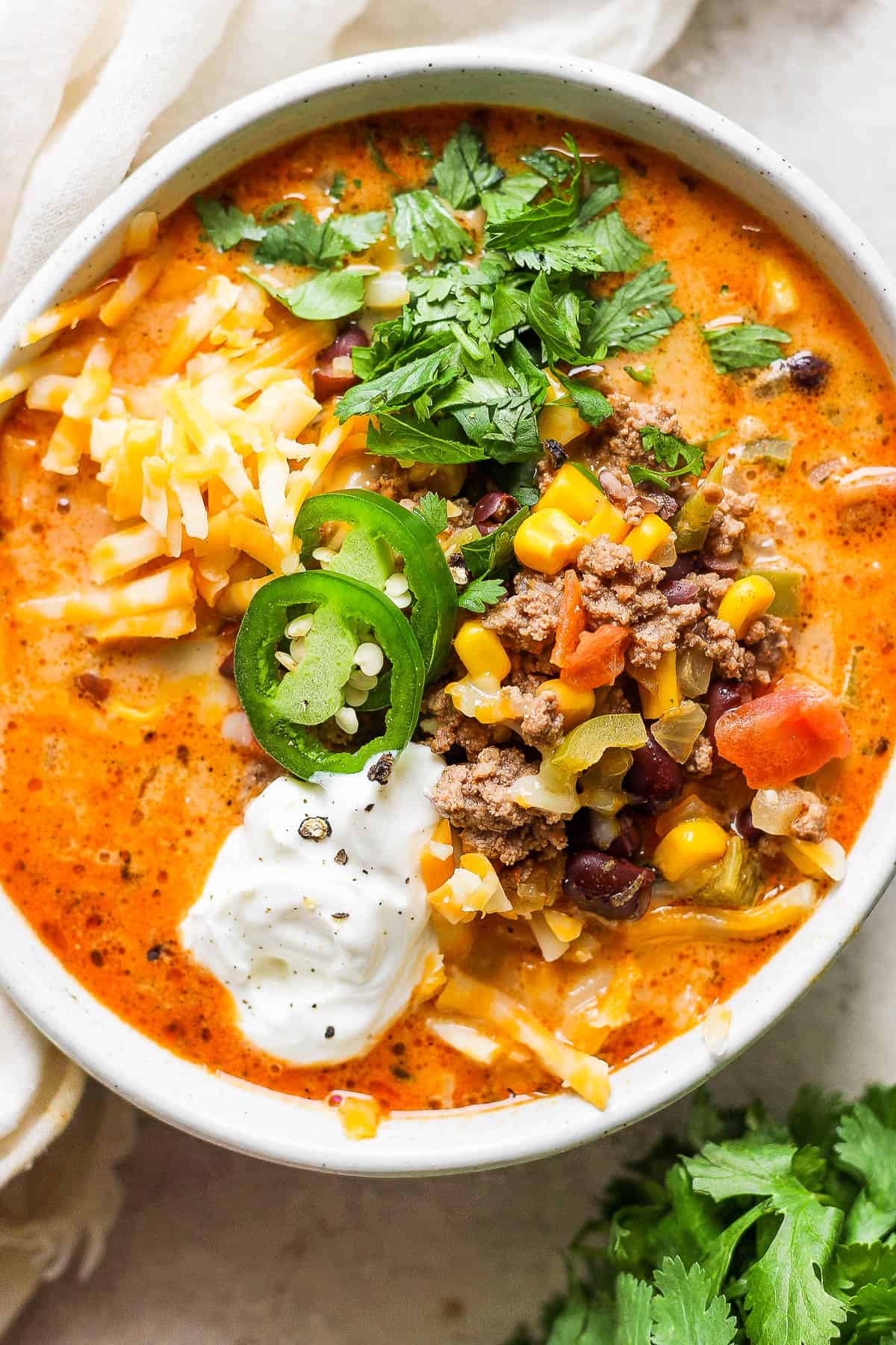 Creamy taco soup in a white bowl with lots of toppings.