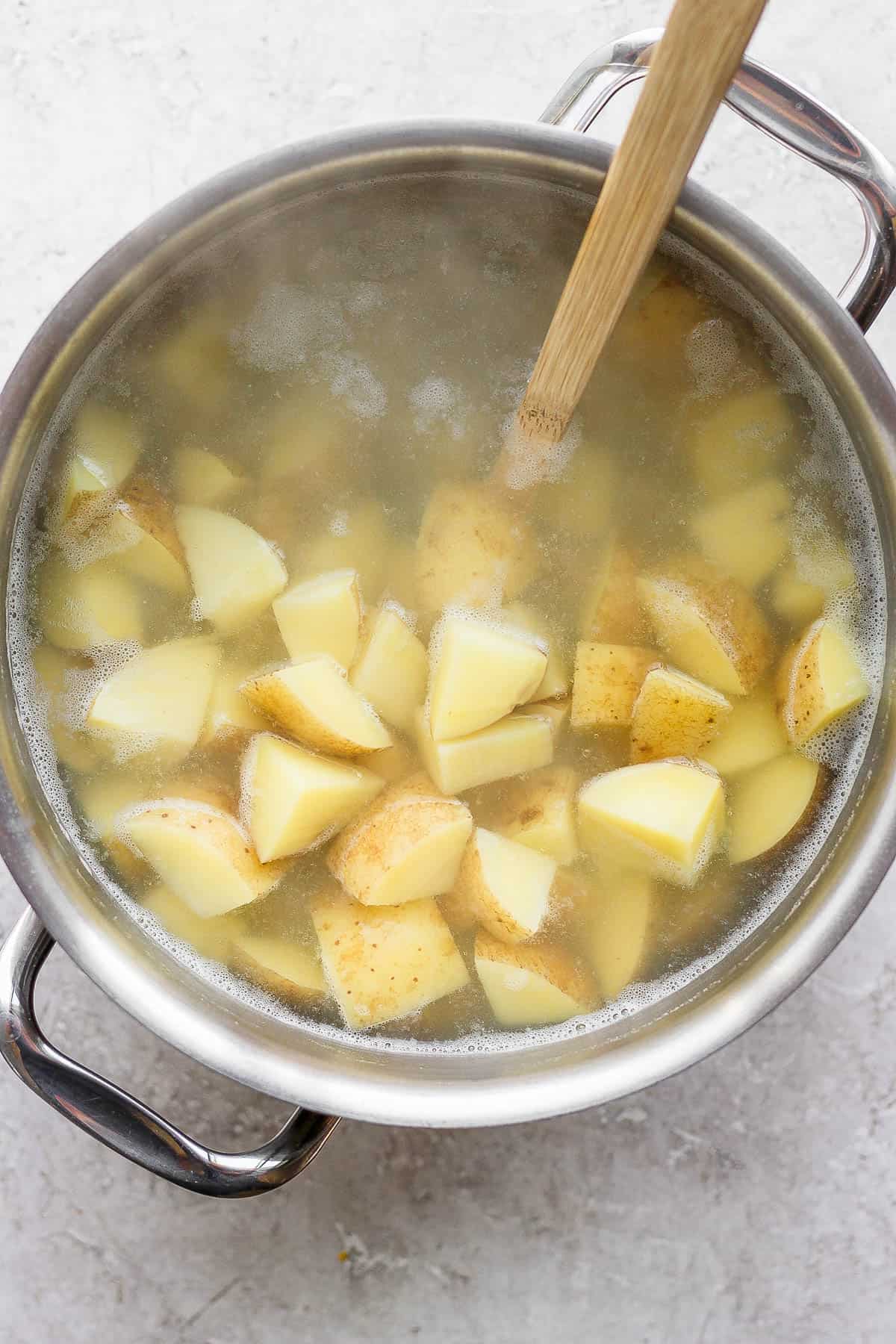 Quartered potatoes in a large stock pot with boiling water.