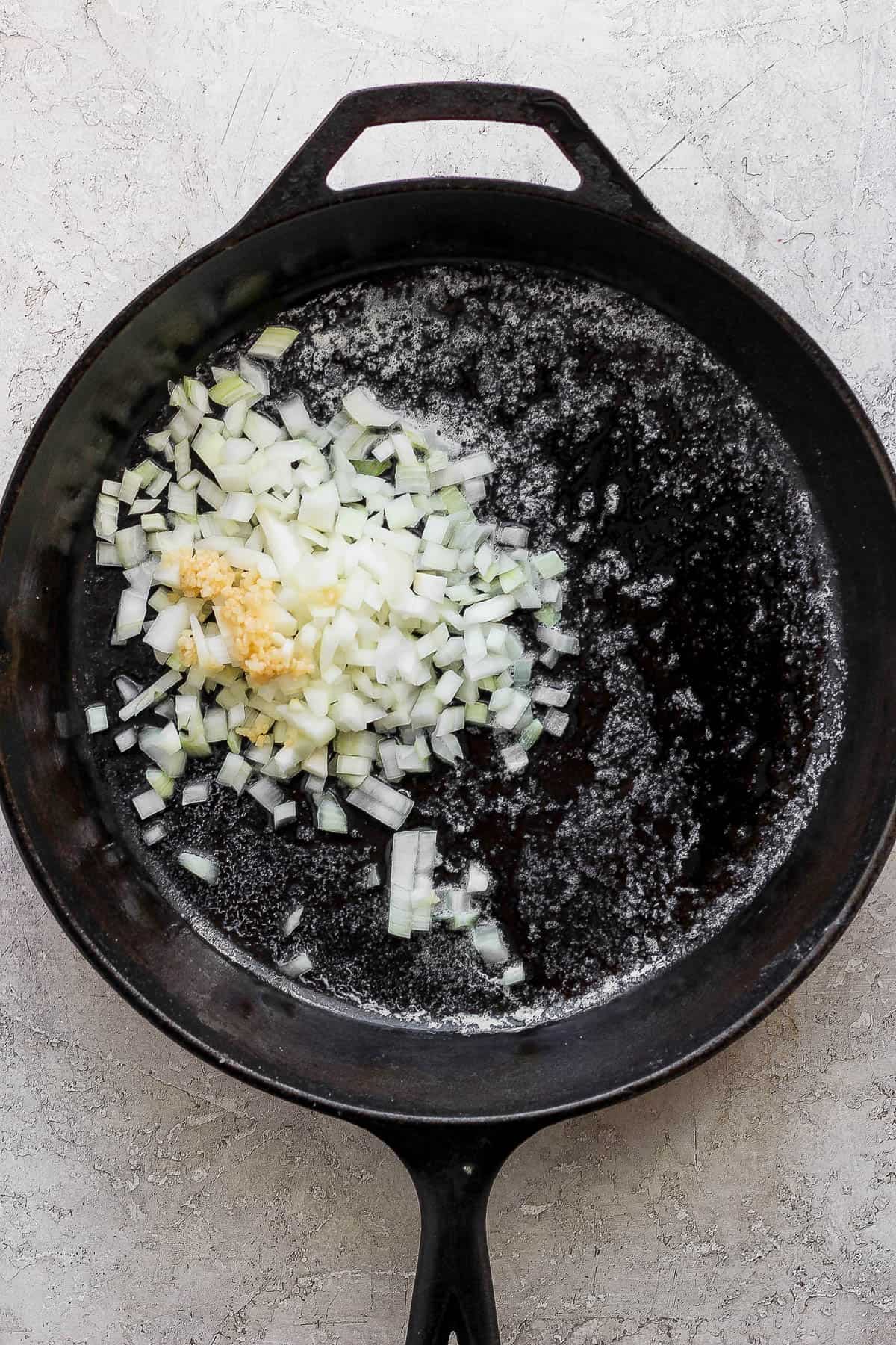 Onion and garlic added to melted butter in a hot skillet.