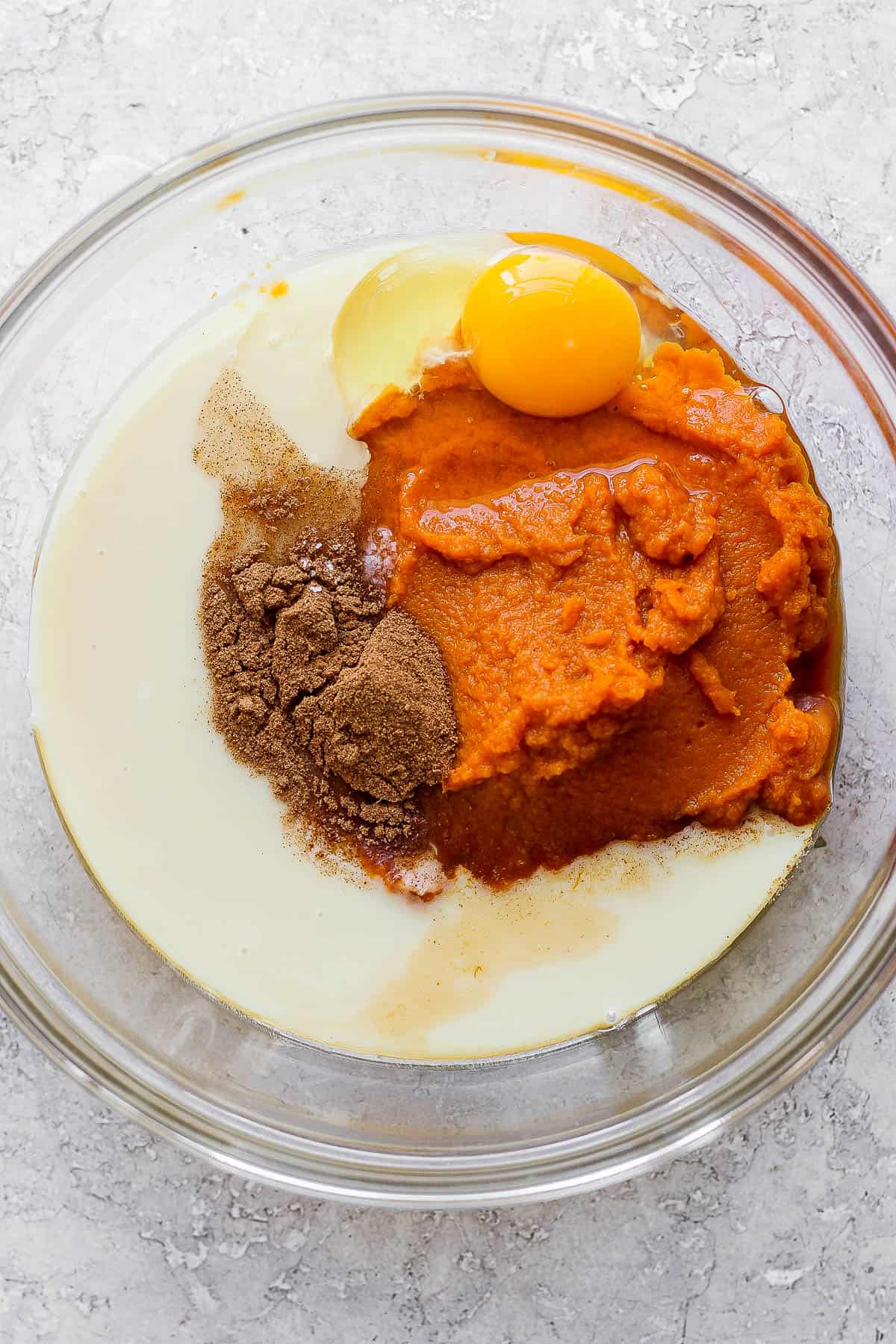 Pumpkin pie filling ingredients in a glass bowl.