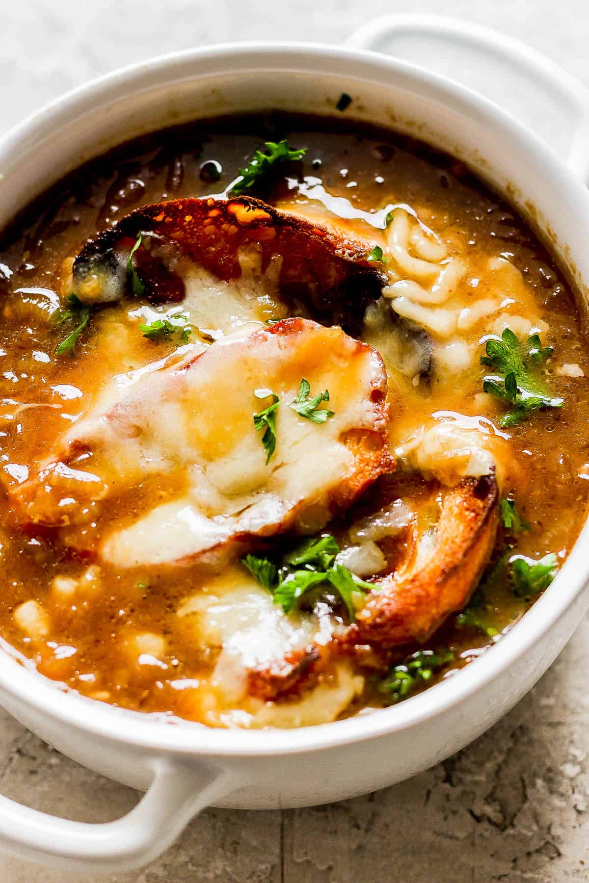French onion soup in a bowl topped with crusty bread and cheese.