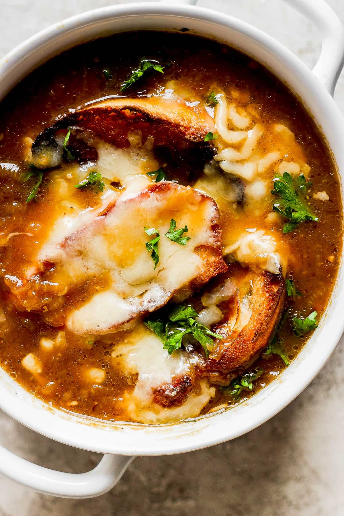 French onion soup in a bowl garnished with fresh parsley.