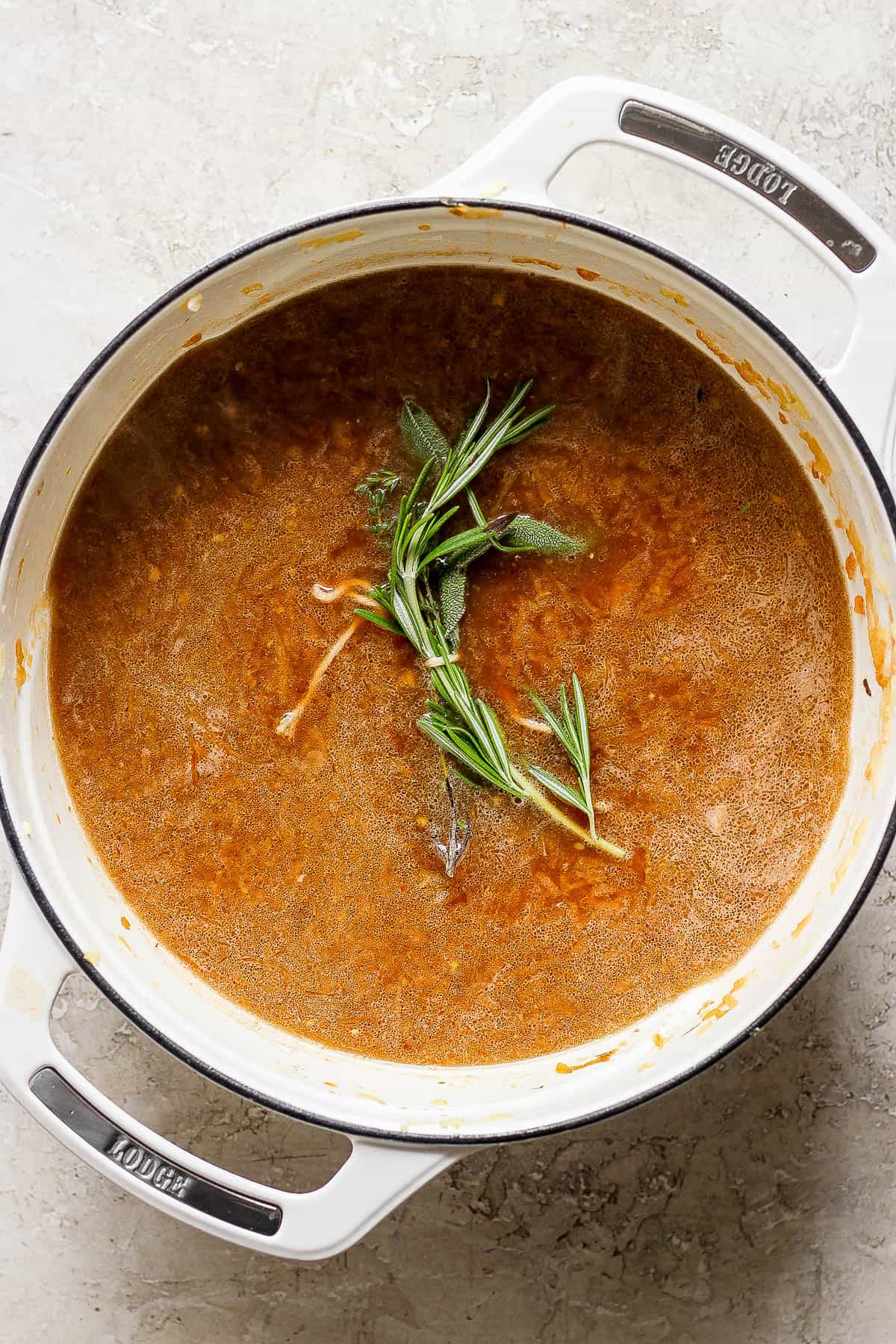 Broth added to the dutch oven plus an herb bundle.