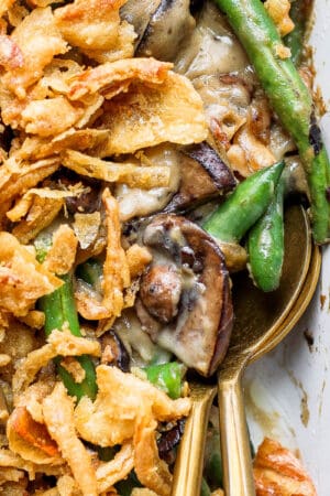 Top down shot of two spoons sticking out of a pan of gluten free green bean casserole with french fried onions on top.