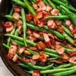 Top down shot of a cast iron skillet filled with cooked green beans with bacon.