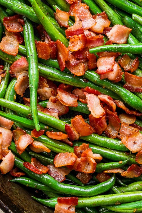 Top down shot of a cast iron skillet filled with cooked green beans with bacon.