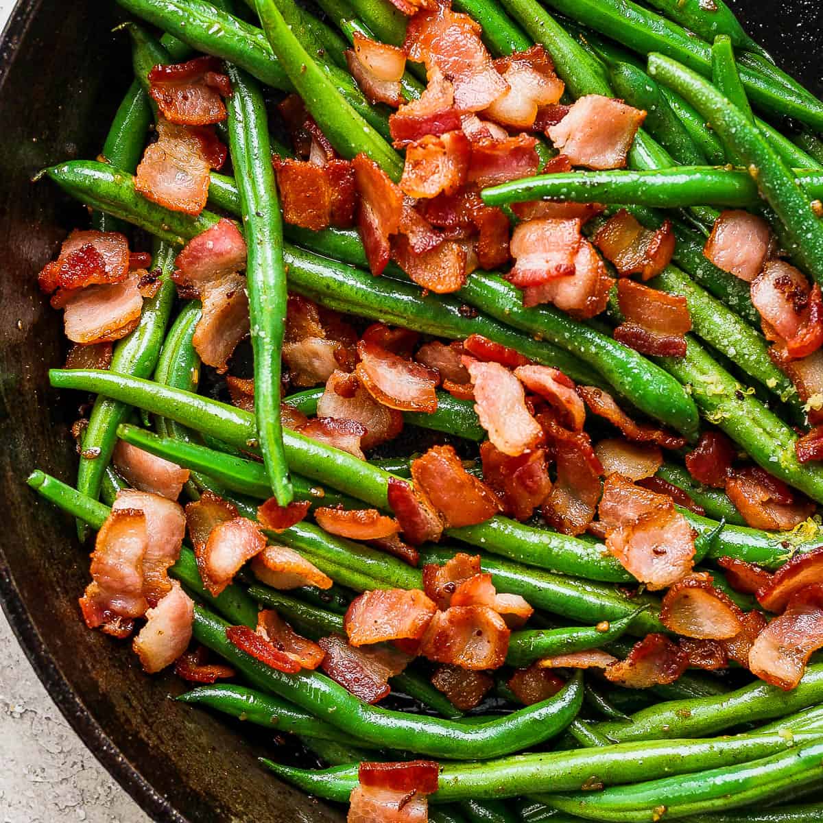 Top down shot of a cast iron skillet filled with cooked green beans with bacon.