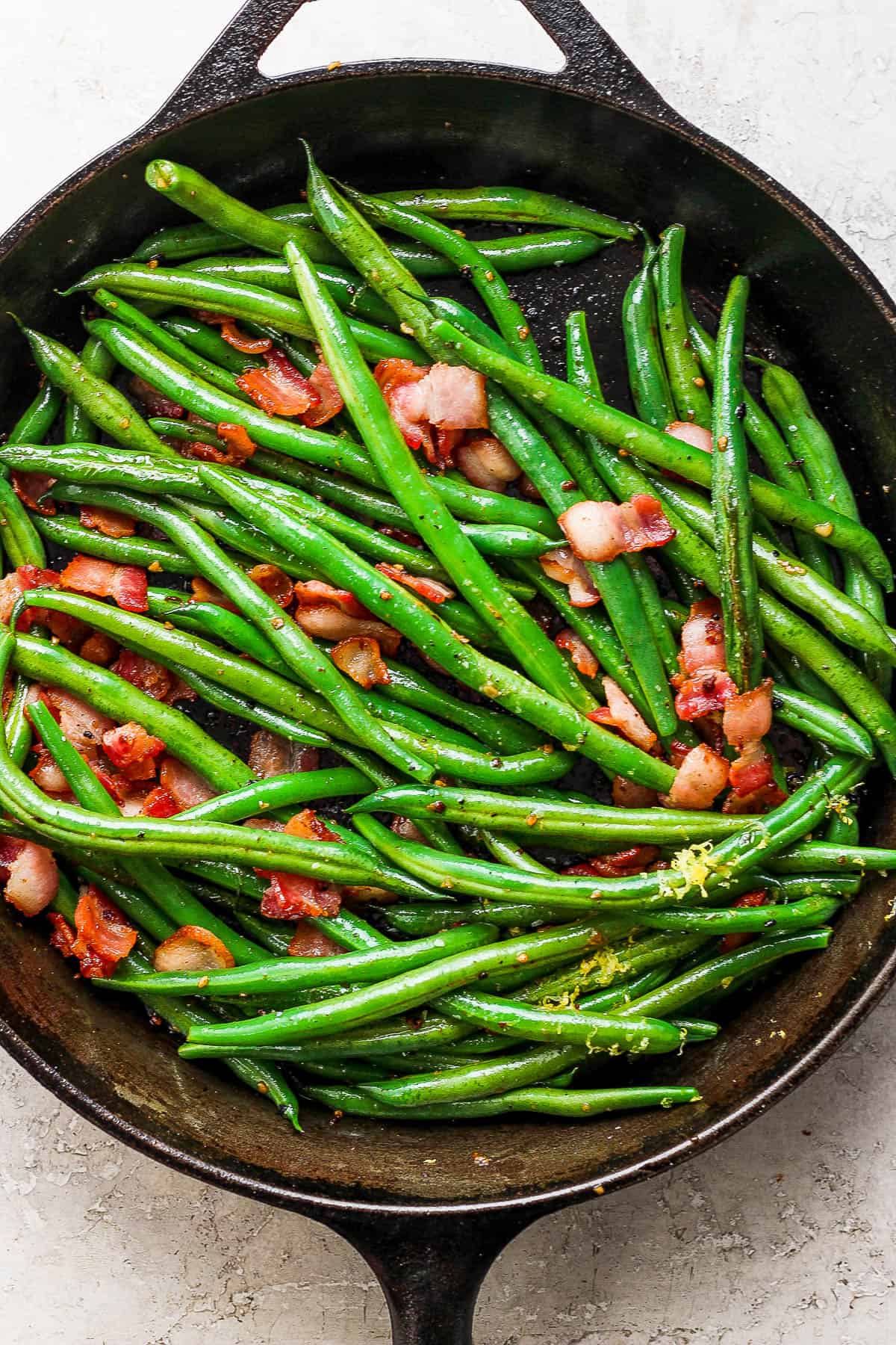 Bacon, lemon zest, garlic, and green beans in the cast iron skillet.