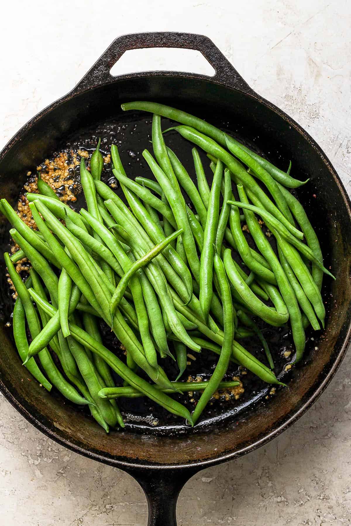 Green beans in the cast iron skillet with minced garlic.