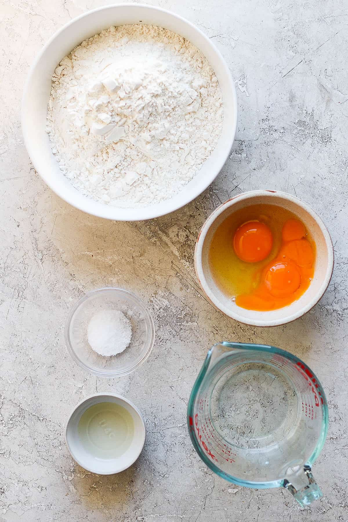 Ingredients for homemade egg noodles in separate bowls.