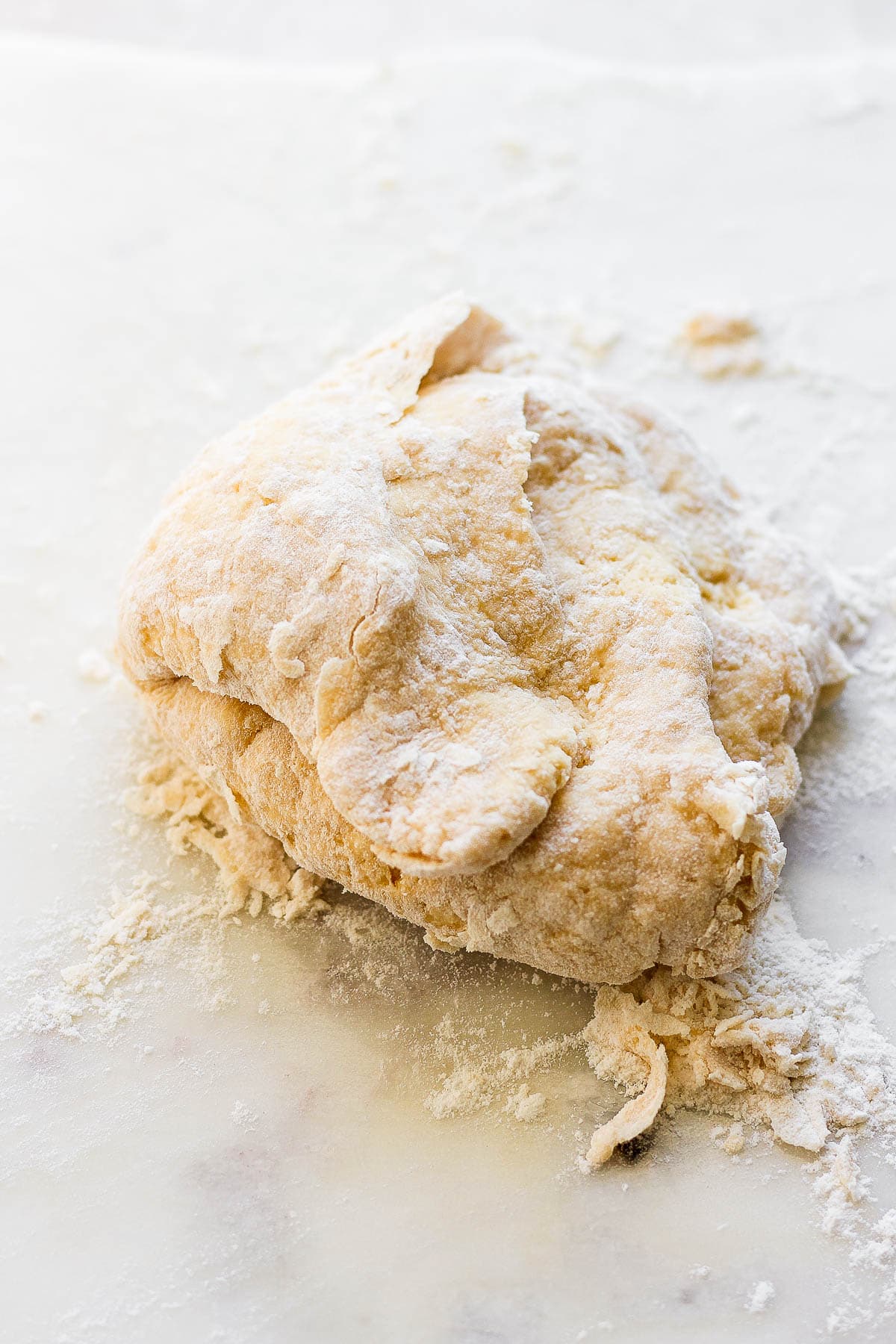 The ball of dough on the counter with some flour sprinkled around it.