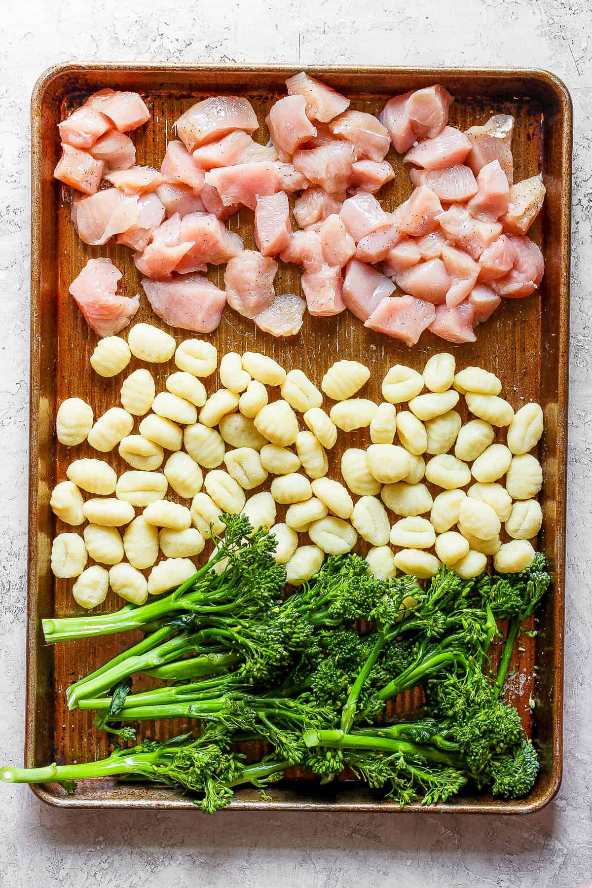 Cubed chicken, gnocchi, and broccolini on a sheet pan.