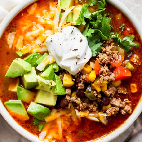 Top down shot of a bowl of taco soup with avocado, cilantro, cheese and sour cream on top.