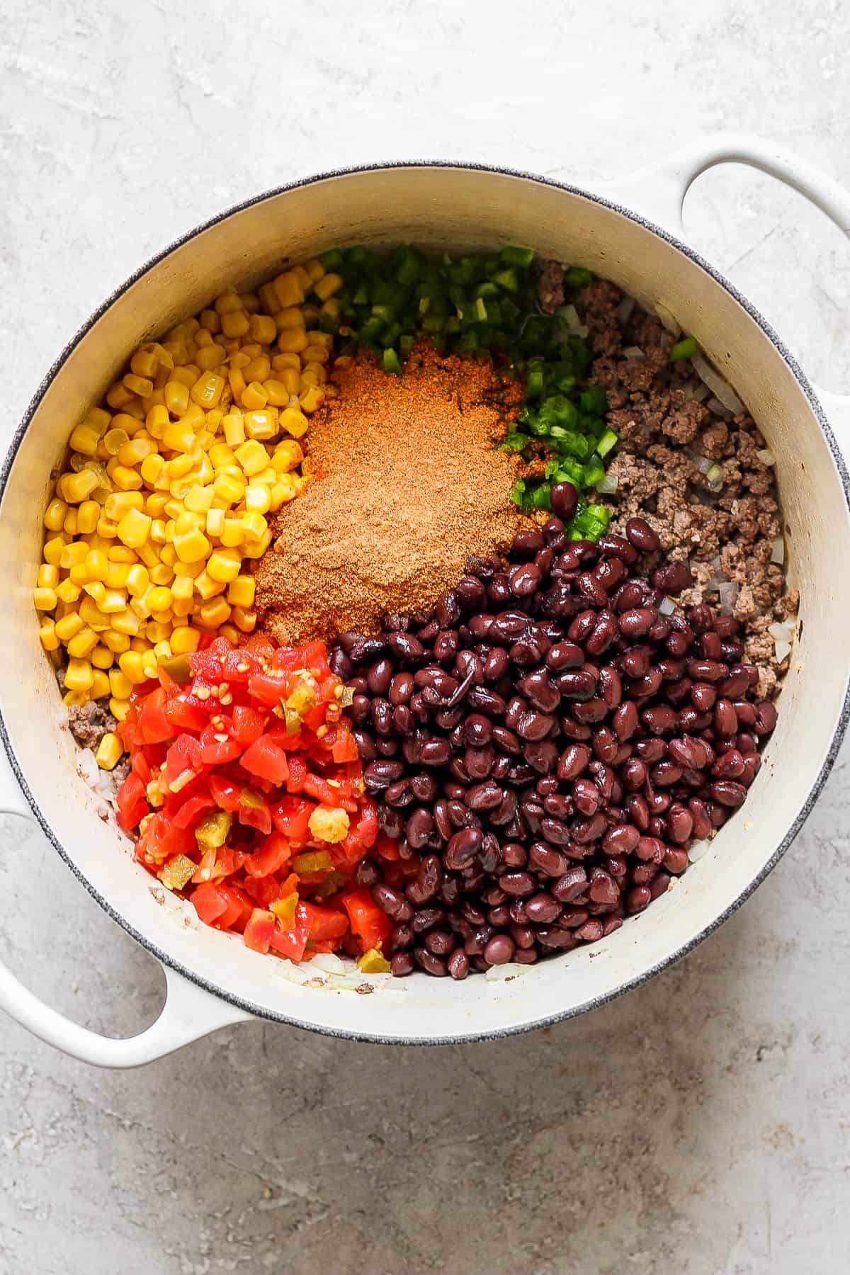 Corn, peppers, diced tomatoes, black beans, and seasoning added to the pot.