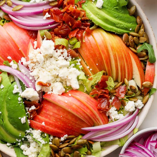 Top down shot of a bowl of a Thanksgiving Salad with apples thinly sliced, red onion, feta crumbles and avocado.