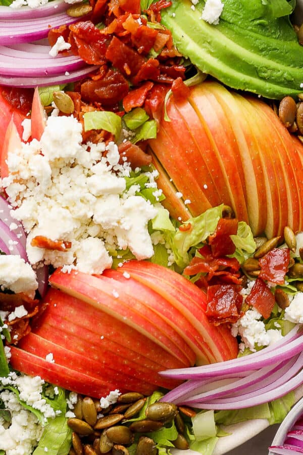 Top down shot of a bowl of a Thanksgiving Salad with apples thinly sliced, red onion, feta crumbles and avocado.