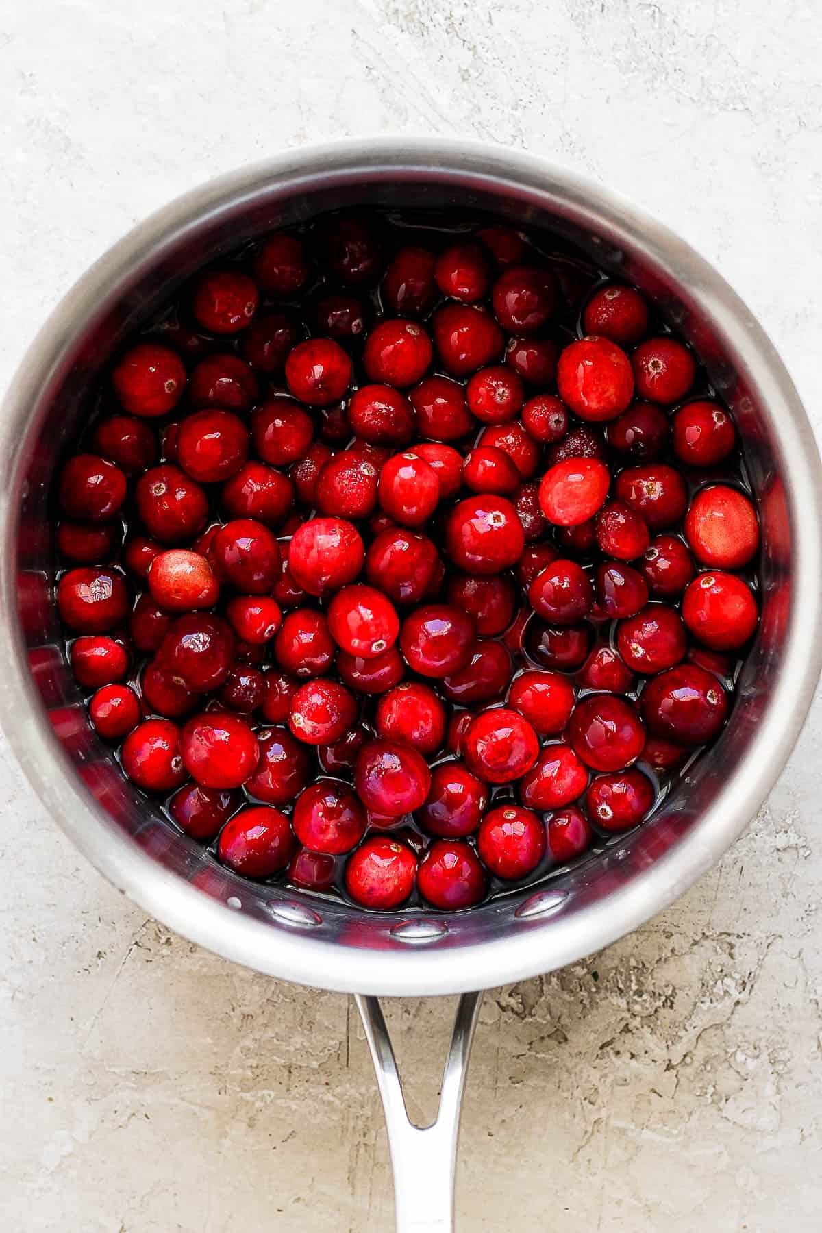 Cranberries in water in a sauce pan.