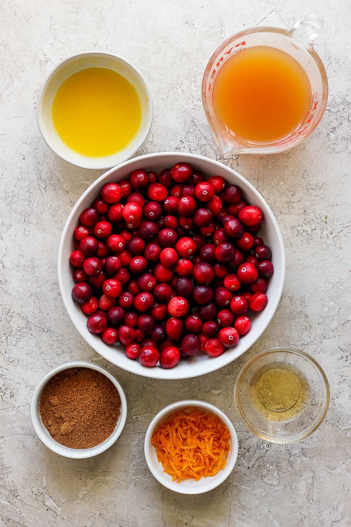 Individual bowls of fresh cranberries, orange juice, orange zest, bourbon, brown sugar, and apple cider.