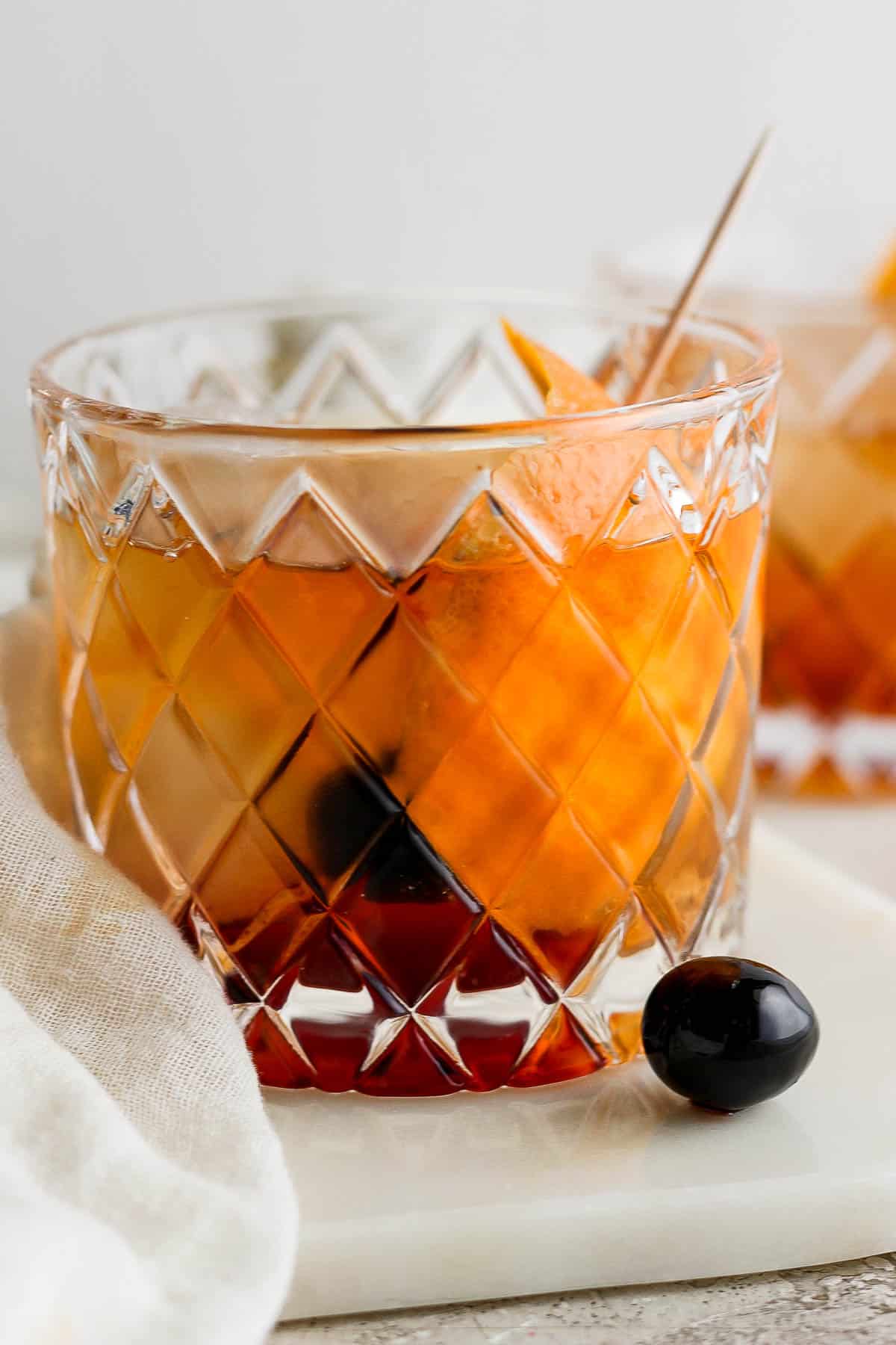 Brandy old fashioned in a low ball glass garnished with an orange peel.
