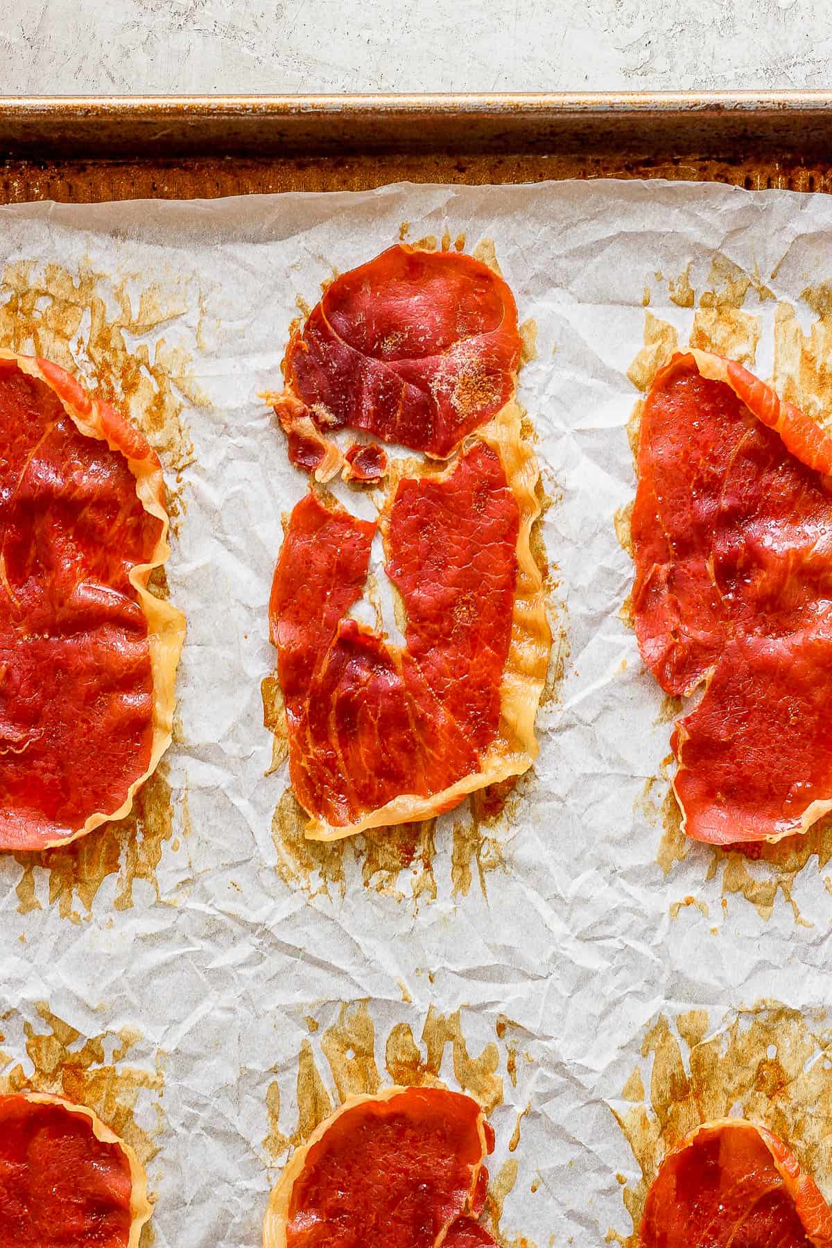 Close-up shot of crispy prosciutto on parchment paper.