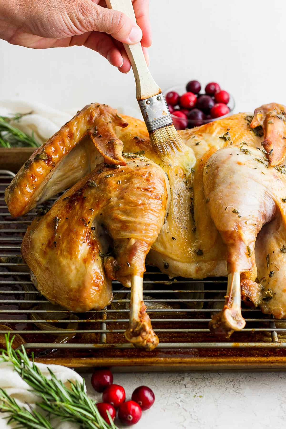 A fully cooked spatchcock turkey being basted with melted butter.