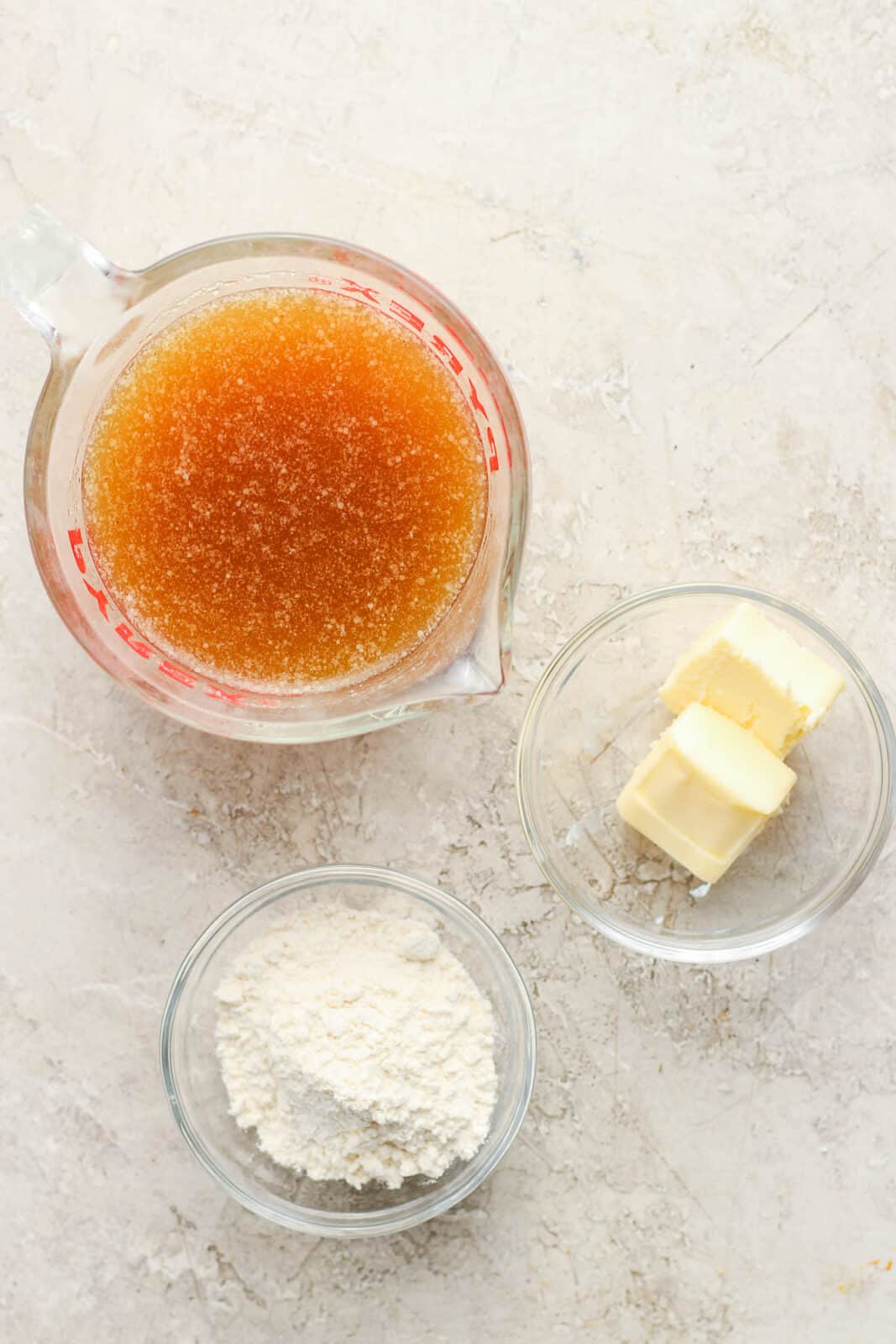 Ham drippings in a measuring cup with a small bowl of butter and flour.