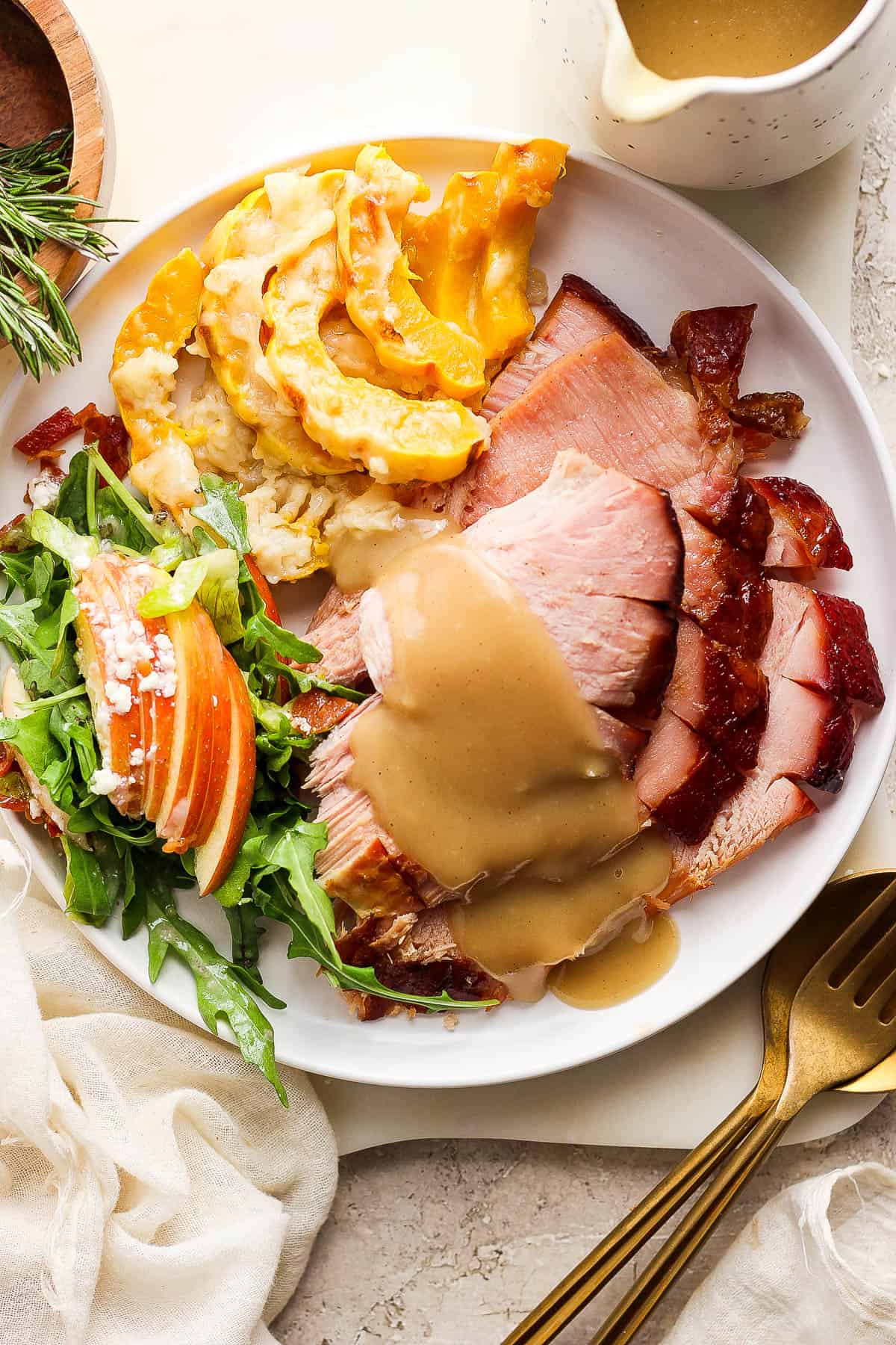 A full plate of ham and sides with gravy poured over the ham.