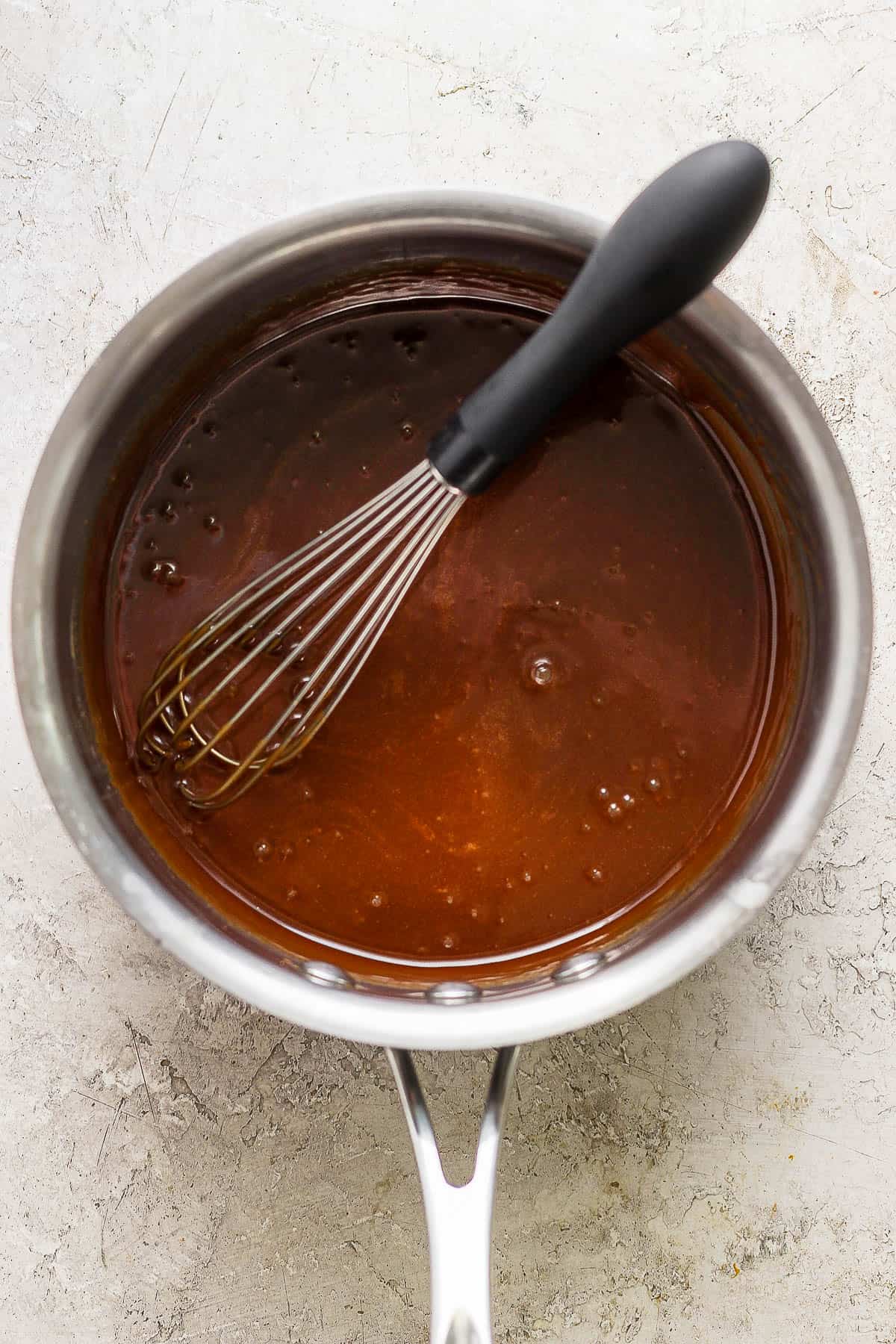 A small metal saucepan with the caramel sauce and a whisk.