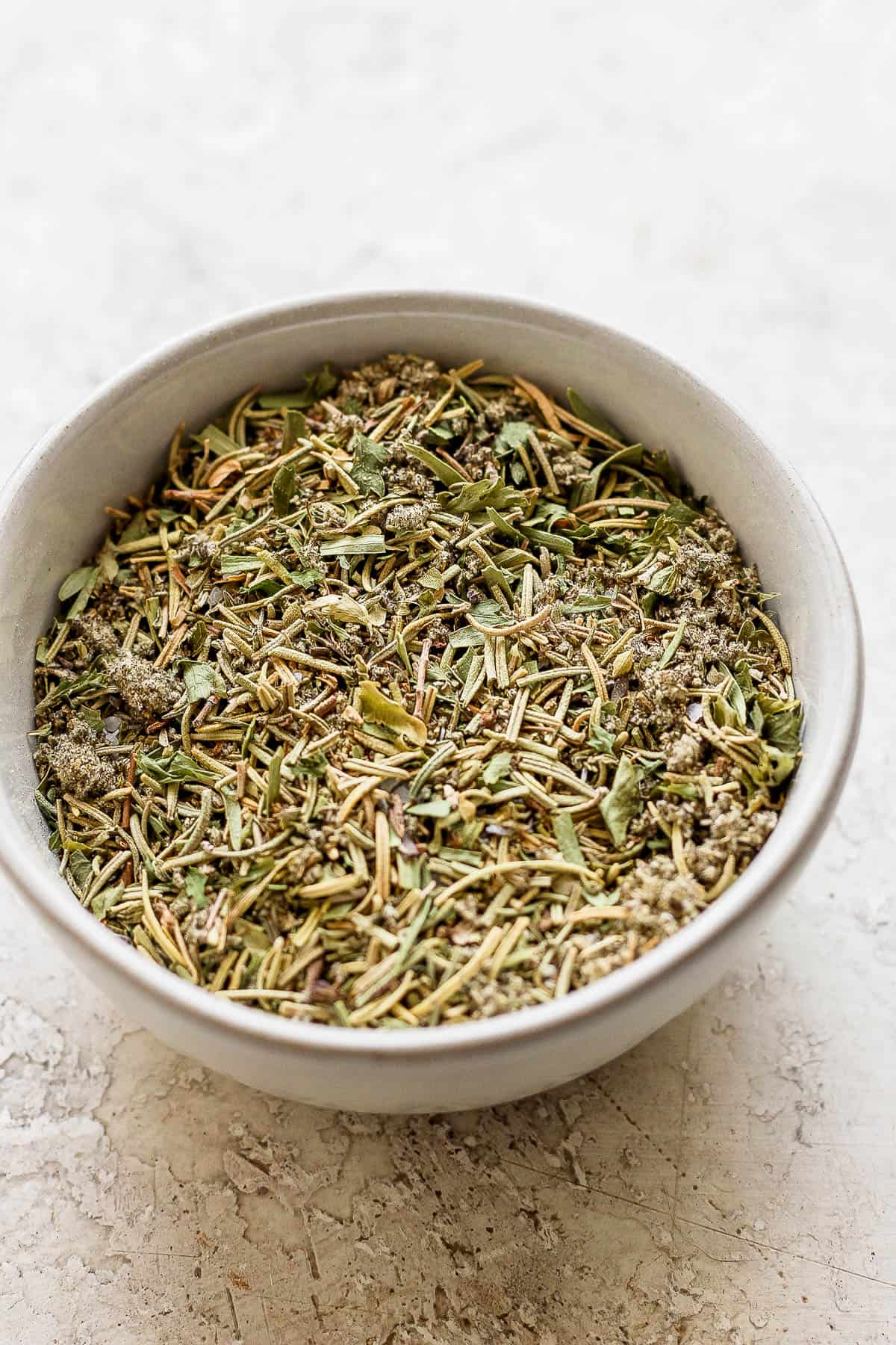 The dried herbs and spices mixed together in a small white bowl.
