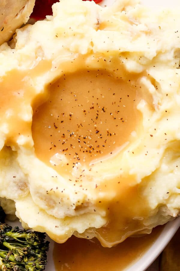 Top down shot of a pile of mashed potatoes covered in make ahead gravy.