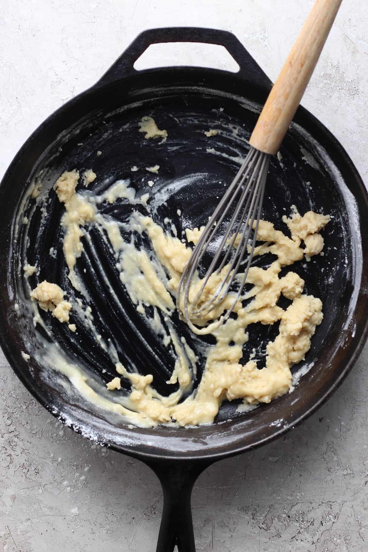 Cast iron skillet with butter and flour mixture with a whisk.