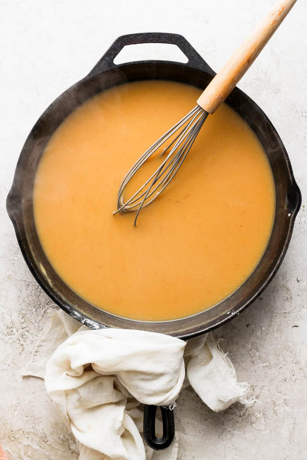 Turkey gravy in a cast iron skillet with a whisk.