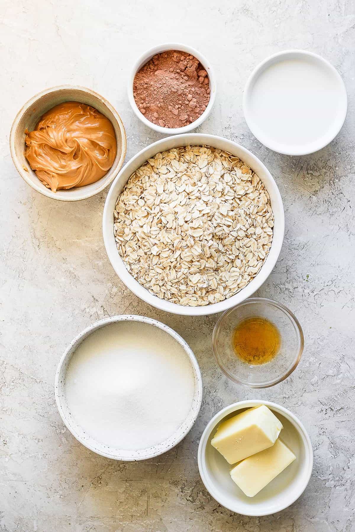 Individual bowls of butter, sugar, vanilla, oats, peanut butter, milk, and cocoa powder.