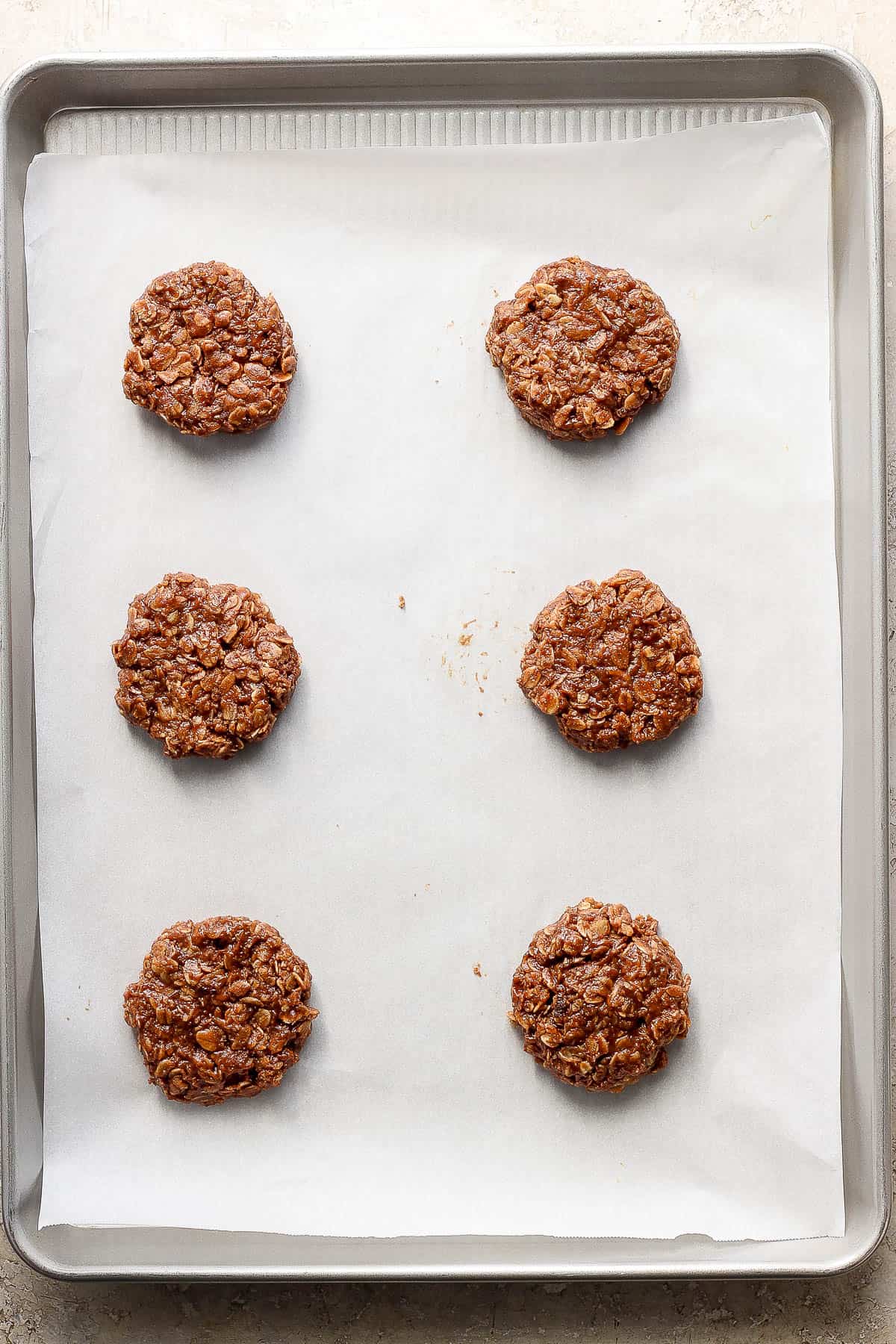 Six no bake cookies on a wax paper lined baking sheet.