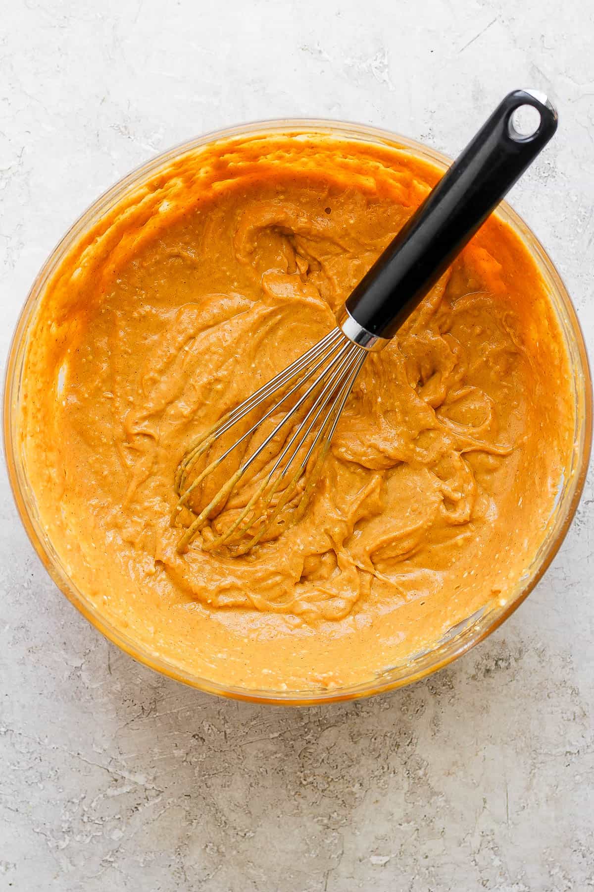 The pumpkin filling whisked together in a glass bowl with the whisk.