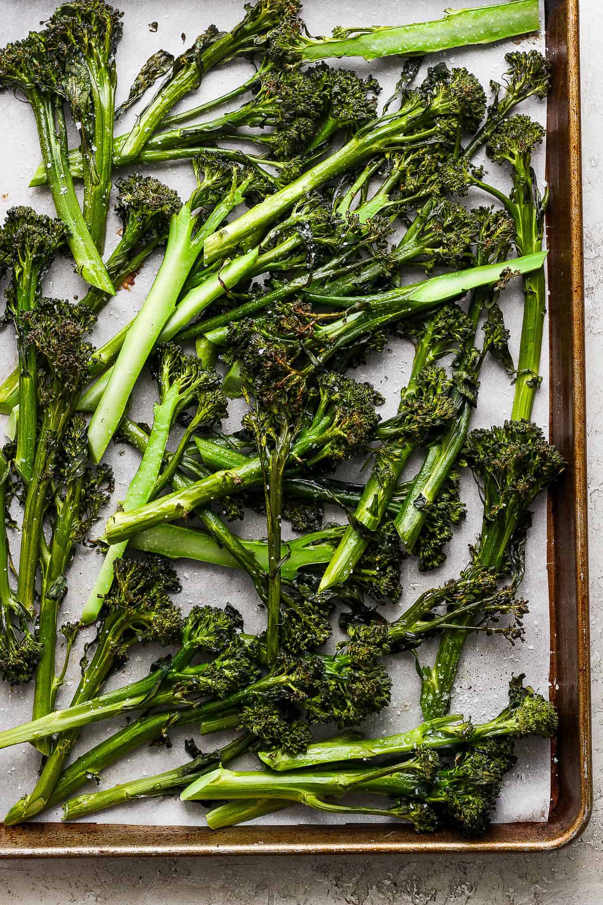 Roasted broccolini on a baking sheet after coming out of the oven.
