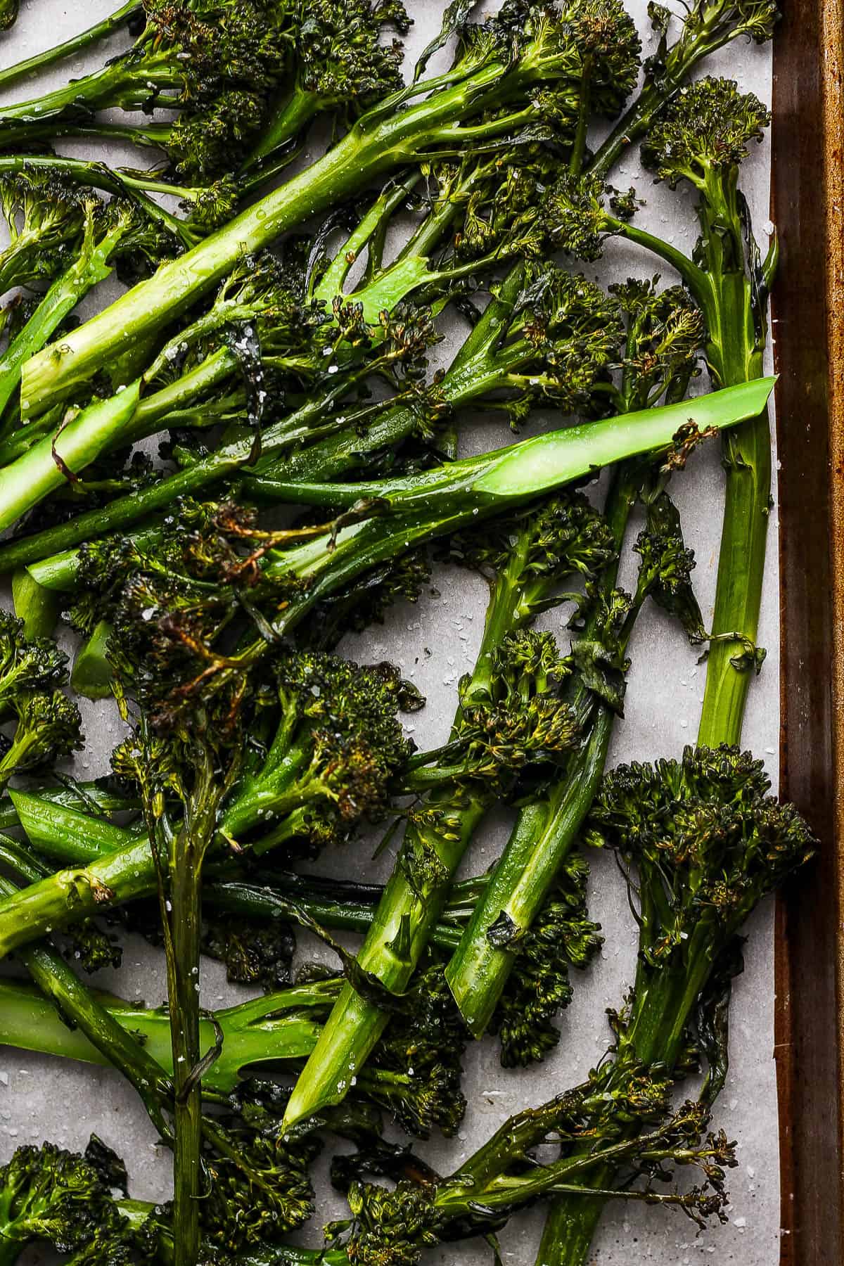 Close-up shot of roasted broccolini on the baking sheet.