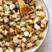 A wooden spoon in some stove top stuffing that is cooking in a braiser.
