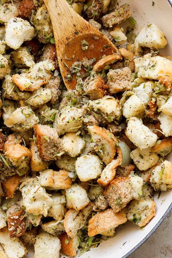 A wooden spoon in some stove top stuffing that is cooking in a braiser.