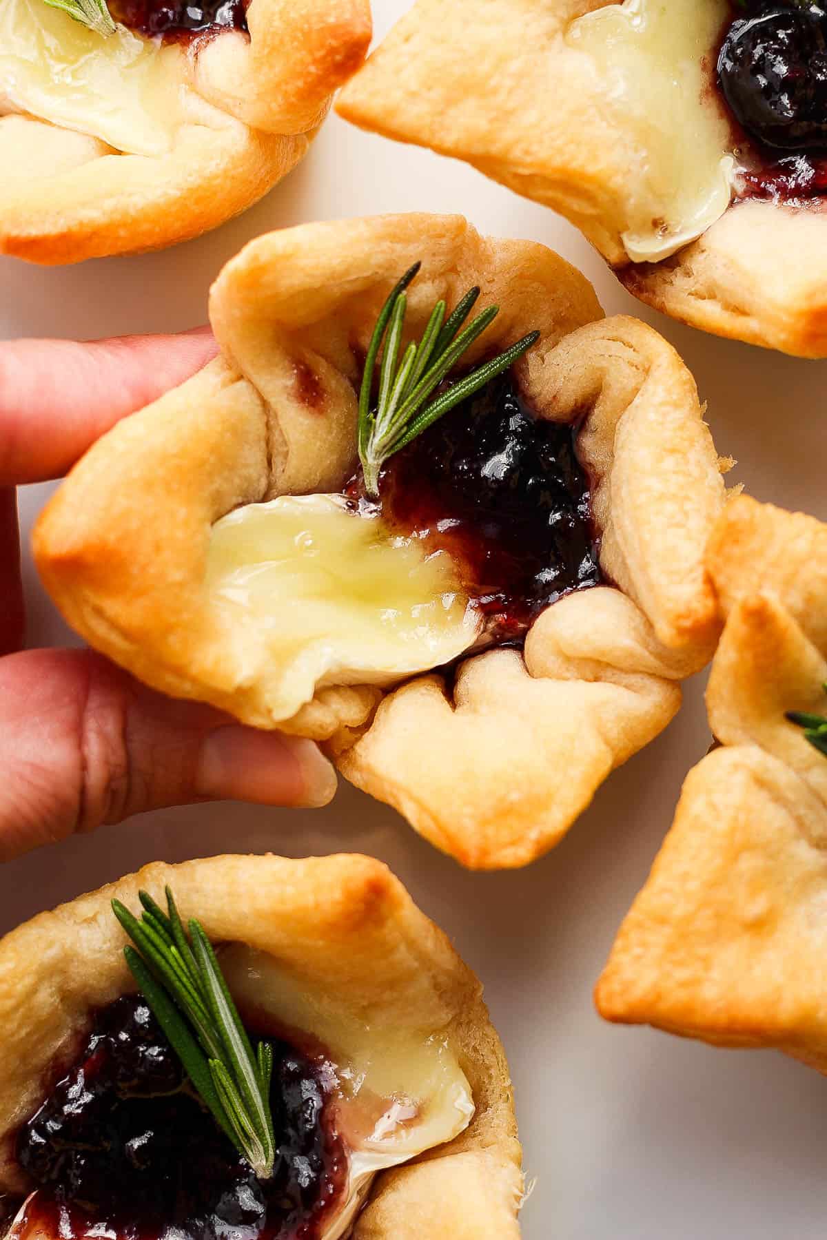 A hand holding a baked brie bite.